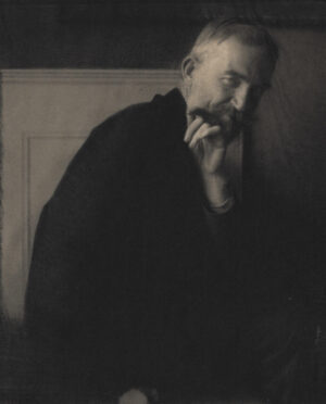 A man with a beard is leaning against the wall