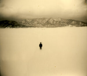 A person standing in the middle of an empty lake.