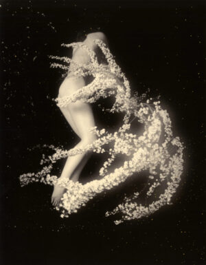 A woman is dancing in the dark with white flowers.