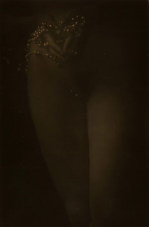 A woman standing in the dark with her legs crossed.