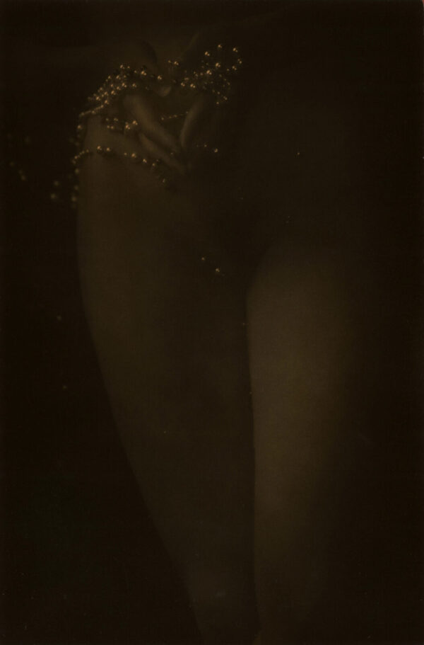 A woman standing in the dark with her legs crossed.