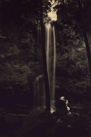 A black and white photo of a waterfall at night.