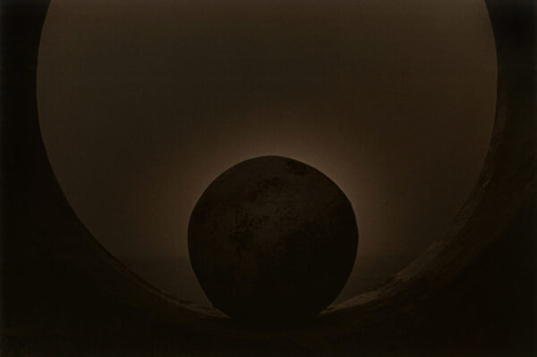 A black hole in the sky with a sun behind it.