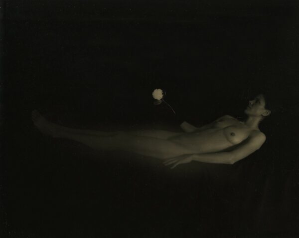 A naked woman floating in the air with her arms outstretched.