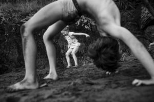 A man is doing a handstand with another man standing behind him.