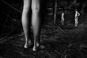 A person standing in the woods with their legs crossed.