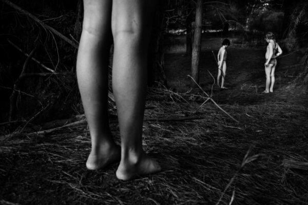 A person standing in the woods with their legs crossed.