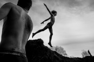 A man jumping in the air over rocks.