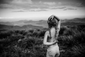 A woman with long hair is standing in the grass.
