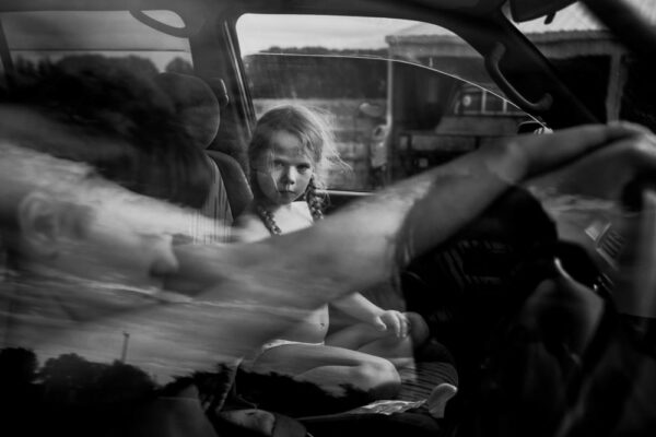 A young girl sitting in the back of a car.