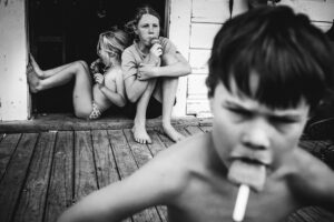 A boy is smoking while two girls sit on the steps.