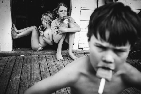A boy is smoking while two girls sit on the steps.