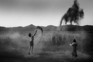 A man and woman in the desert playing with a kite.