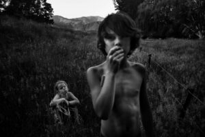A young boy and girl in the grass.