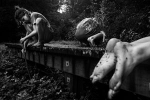 A black and white photo of some people sitting on the side of a road.