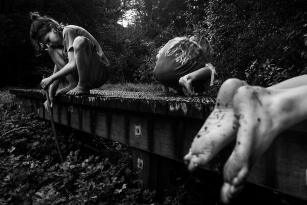 A black and white photo of some people sitting on the side of a road.