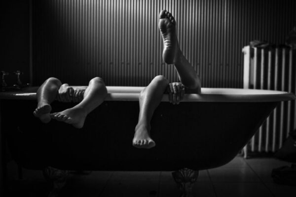 A man laying in the bathtub with his feet up.