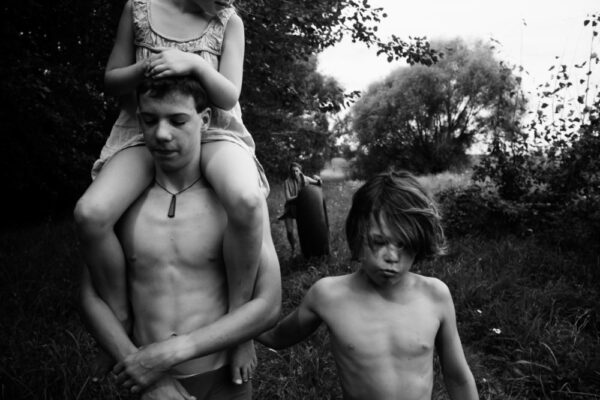 A man and two boys are standing in the grass.