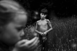 A boy is standing in the grass eating.
