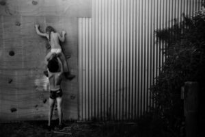 A couple of kids climbing up the side of a wall.