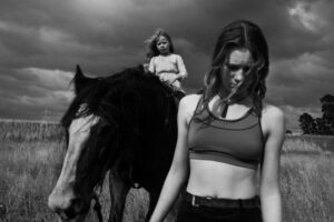 A woman standing next to a horse in front of another woman.