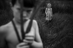 A young girl holding a stick in the grass.