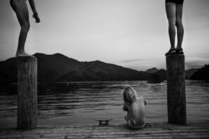 A woman sitting on the dock of a lake.