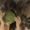 A woman hiding her face behind a leaf.