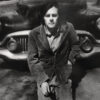 A man standing in front of an old car.