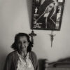 A woman standing in front of a cross and picture.
