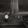 A young child standing next to a tree.