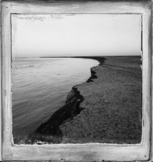 A black and white photo of the ocean shore.