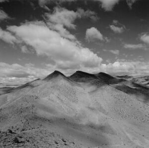 A black and white photo of some mountains in the desert