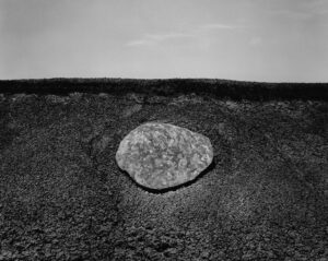 A rock sitting on top of a dirt field.