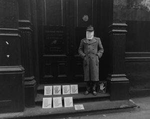 A man in uniform standing on steps with newspapers.
