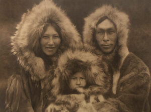 A man and two women with fur coats on.