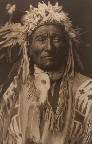 A man in native american garb with feathers.