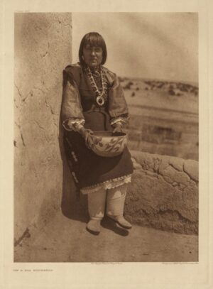 A woman in native dress holding a bowl.