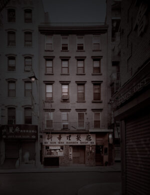 A dark city street with buildings and signs.