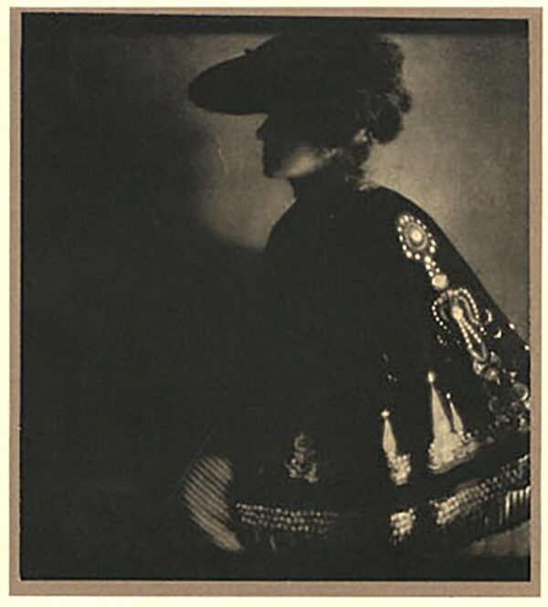 A woman in black and white standing next to a wall.