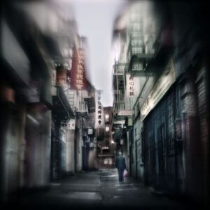 A blurry image of an alley with buildings.