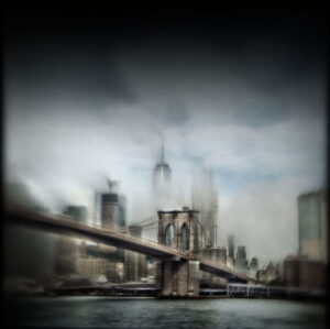 A blurry picture of the brooklyn bridge and the skyline.