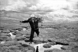 A man holding onto a bicycle in the middle of a puddle.