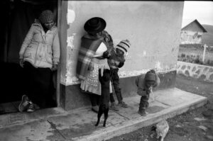 A woman and two children stand outside of a building.