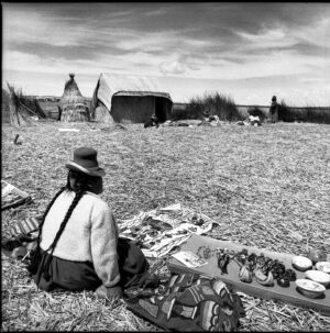 A woman sitting on the ground with many items.