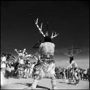 A man in native dress dancing with other people.