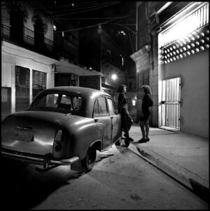 A couple of people standing next to an old car.