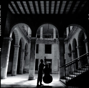 A man standing in an old building with a cello.