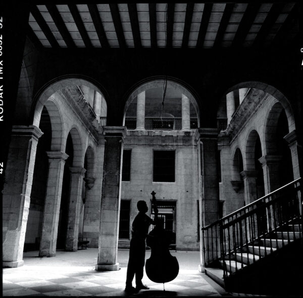 A man standing in an old building with a cello.