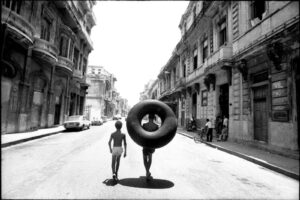 A man and woman walking down the street with an inflatable donut.